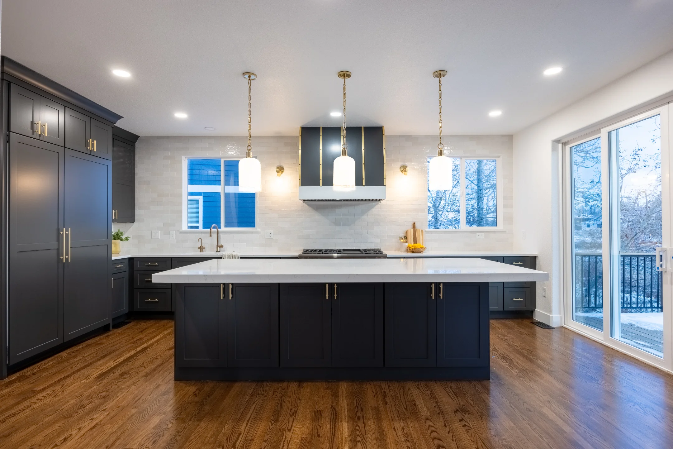 Garden City kitchen with charcoal cabinetry, brass hardware, and a white island
