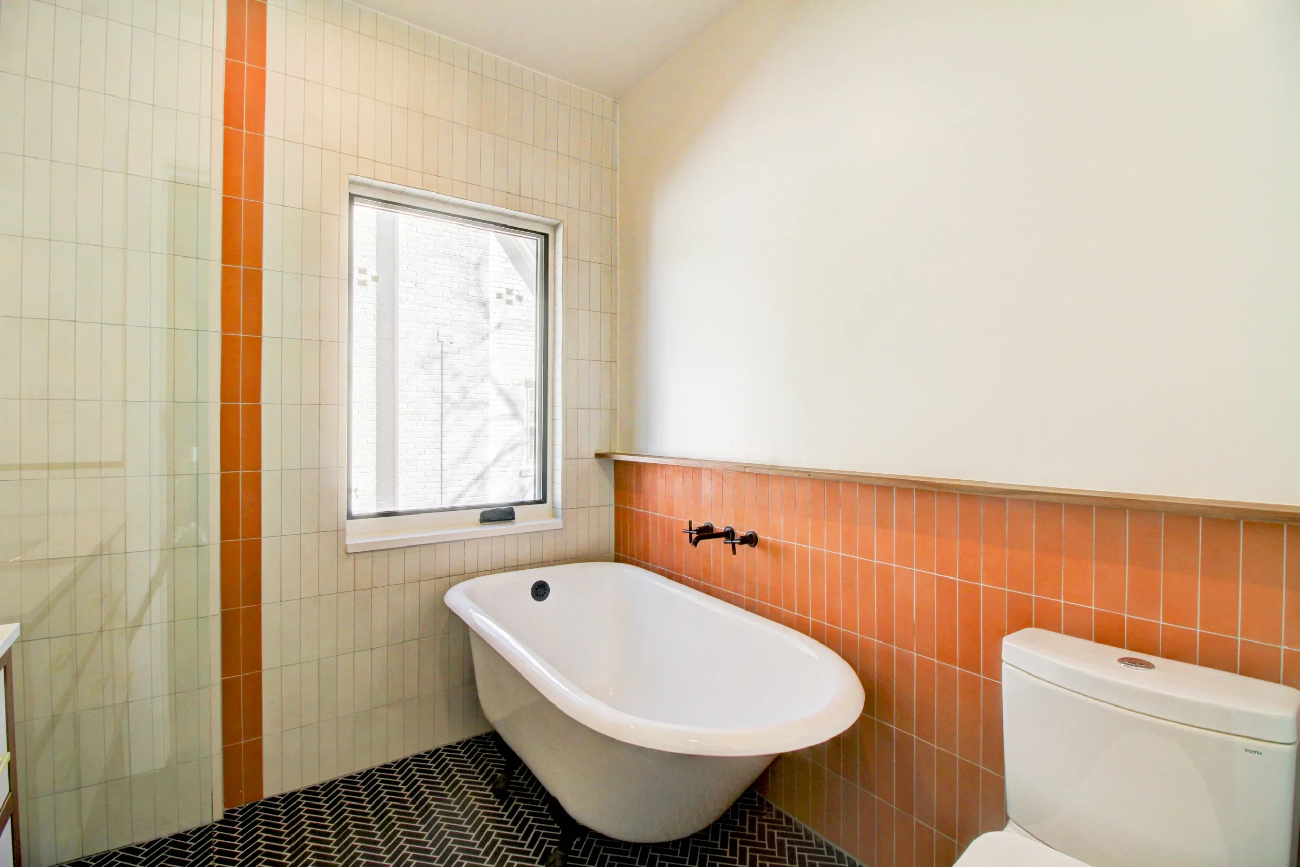 Completed Queens Village bathroom with freestanding tub, custom vanity, and black fixtures